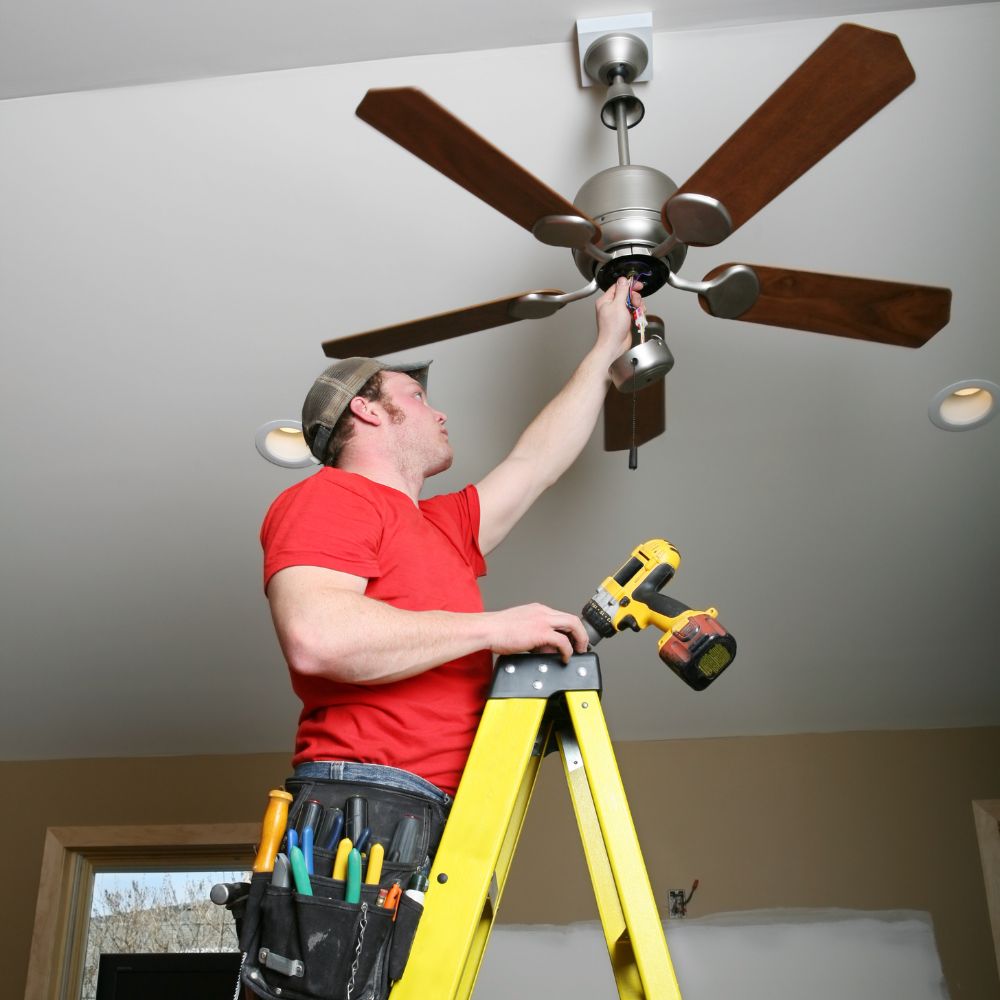 An electrician repairing a ceiling fan.
