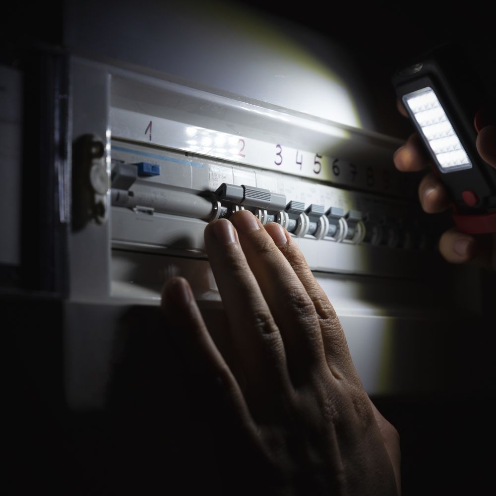 A breaker panel being inspected during a power outage at night.